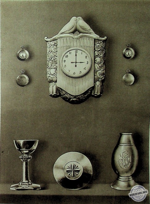 CARTEL (bronze doré) composé par Dieu PART, édité par CONTENOT, <br />BOITIERS DE MONTRES (acier oxydé, incrusté d’argent) par J. DUNAND, <br />CALICE ET PATENE (argent) par A. RIVIR.<br />VASE (argent) par HENIN.